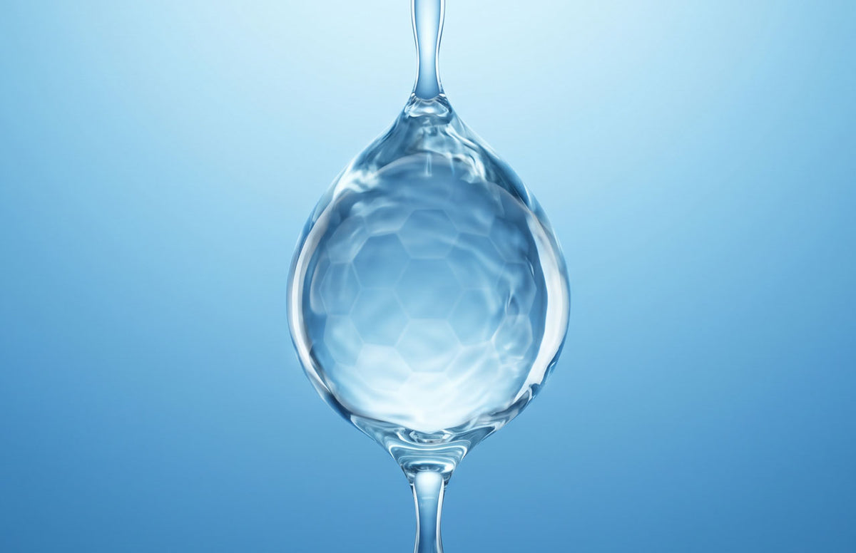 Wassertropfen mit sechseckiger Wabenstruktur im Inneren vor blauem Hintergrund
