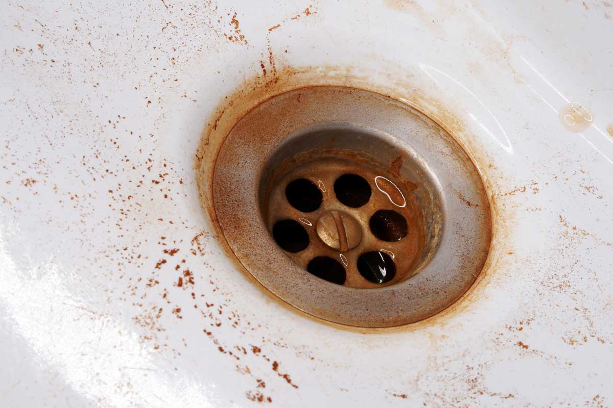 Rostbraune Flecken rund um den Metallabfluss eines weißen Waschbeckens