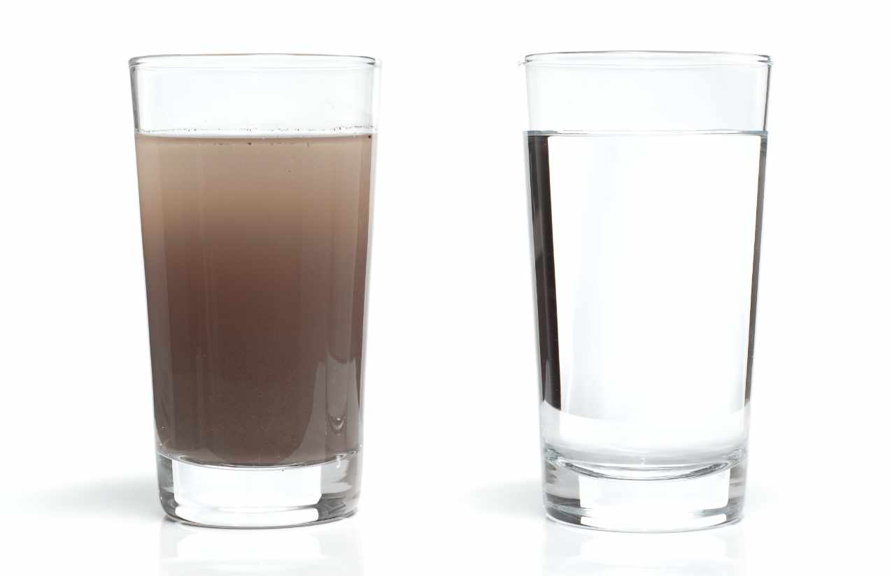 Zwei Wassergläser im Vergleich: links braun getrübtes Leitungswasser, rechts klares Wasser