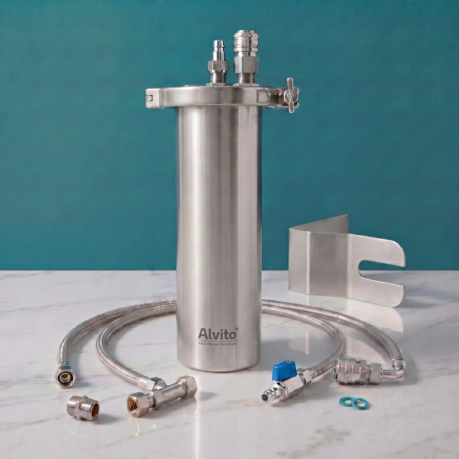 Alvito Inox T Einbaufilter-Set auf weißer Marmorarbeitsplatte – gebürstetes Edelstahlgehäuse mit Wandhalterung und Schnellkupplungen, Aufschrift „Alvito Wasserfilter aus Deutschland", zwei Flexschläuche, O-Ringe, Edelstahl-Montagebügel und Fittings; teal Hintergrund